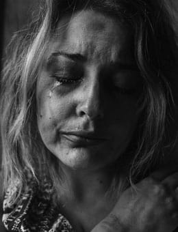 An physically abused woman crying - Codependency may derive from experiencing abusive relationships.