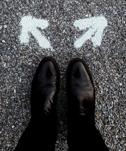 Referrals in Counselling - top view image of a man's shoes with two arrows drawn in chalk on the ground